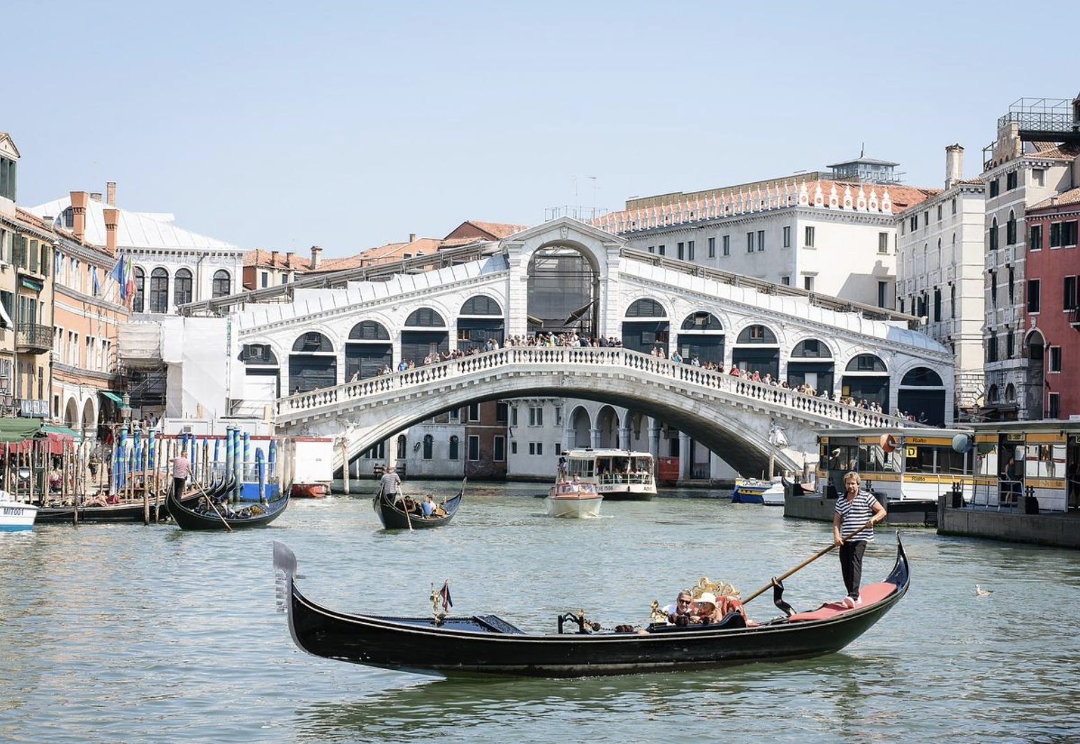 A gondola moves gracefully along a canal in Venice, reflecting the beauty of the surrounding historic landscape.